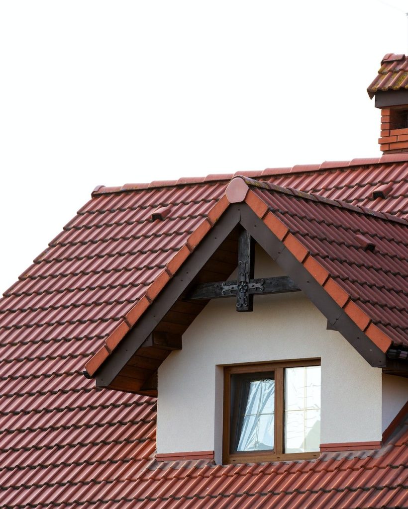 Close up of new orange roof with chimney and small modern window. Concept of modern roof with