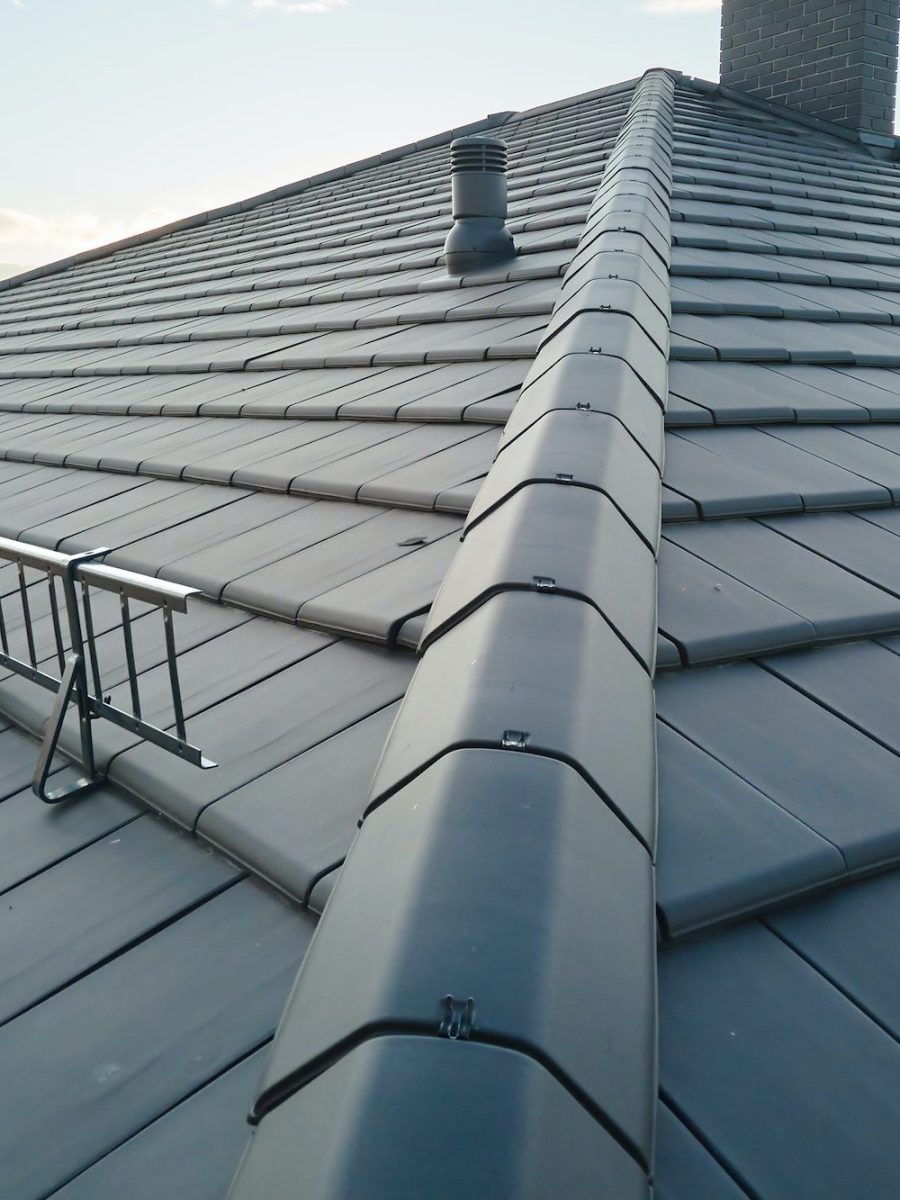 Closeup of house roof top covered with ceramic shingles. Tiled covering of building