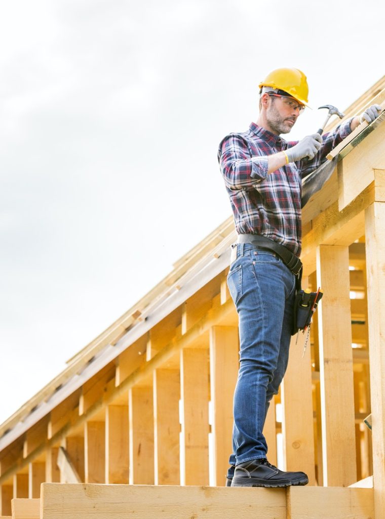 Roofer builder working on roof structure at construction site