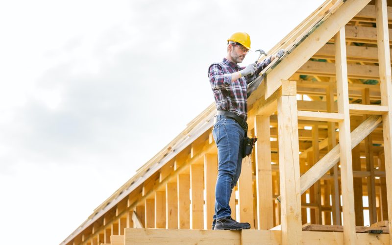 Roofer builder working on roof structure at construction site